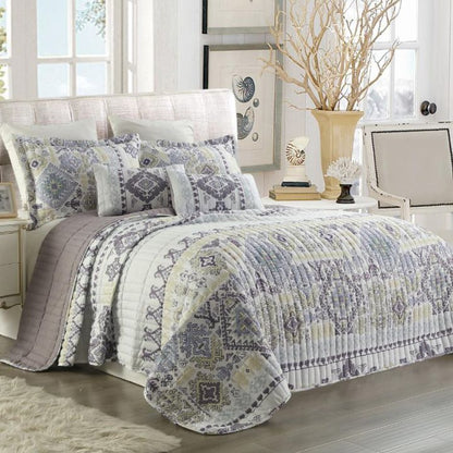 Patterned quilt on a bed in a bedroom setting with decor elements.