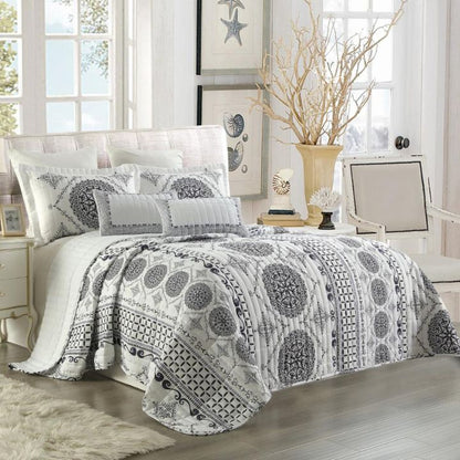 Bedroom with a bed covered in a patterned comforter and pillows.