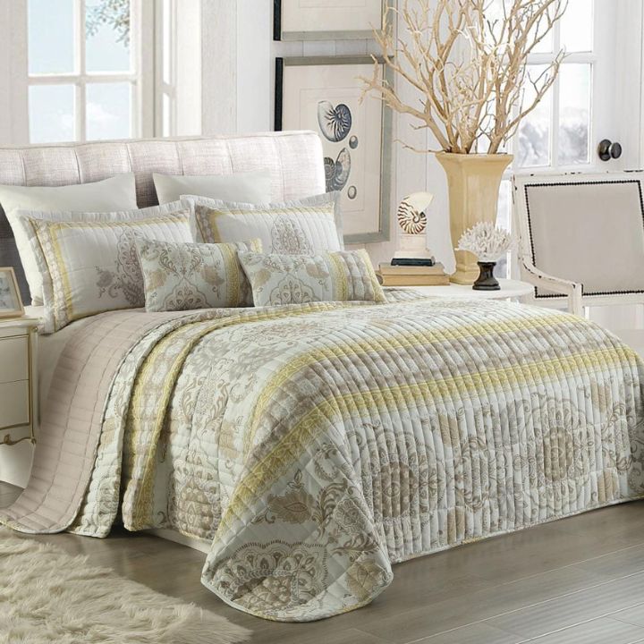 Neatly made bed with patterned bedding in a bright bedroom.