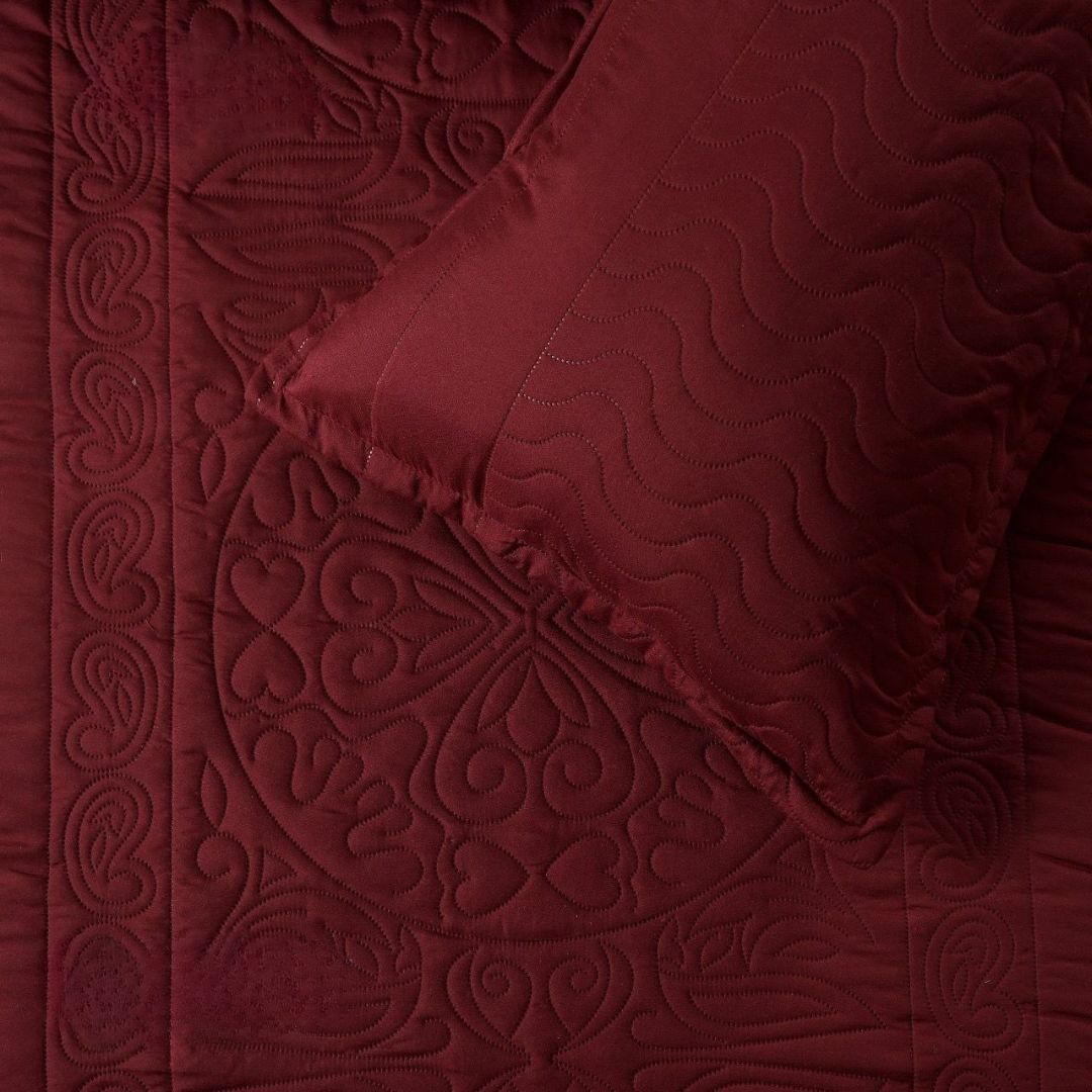 Close-up of a red textured quilt with intricate patterns