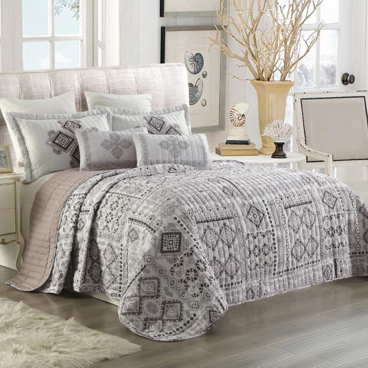 Bedroom with a patterned quilt and pillows on a bed.