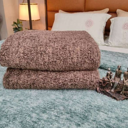 Stack of brown textured blankets on a bed with decorative elements.