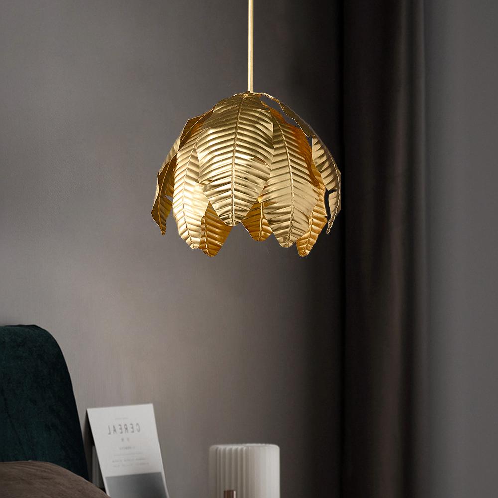Gold palm leaf hanging pendant light from The Gharnish, decorative floor lamp with intricate leaf design and warm gold finish.