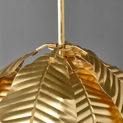 Gold palm leaf hanging pendant light from The Gharnish, stylish floor lamp with a tropical leaf design and warm gold finish.
