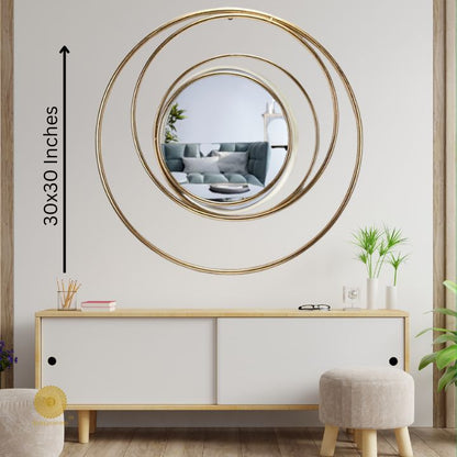 Round metallic wall mirror with a ring of rings design, 30-inch diameter, by The Gharnish, hanging on a wall.