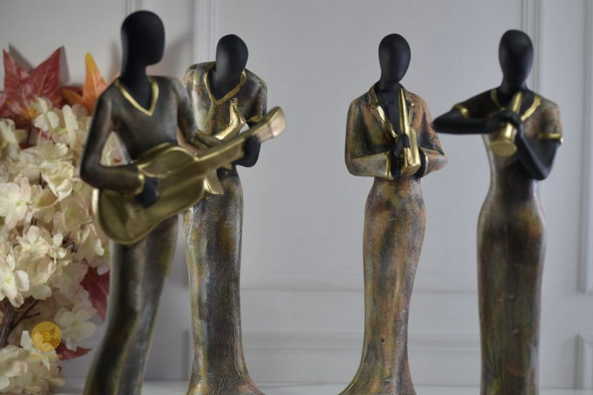 Golden women music band figurine by TheGharnish, detailed sculpture of women playing musical instruments, decorative art piece.