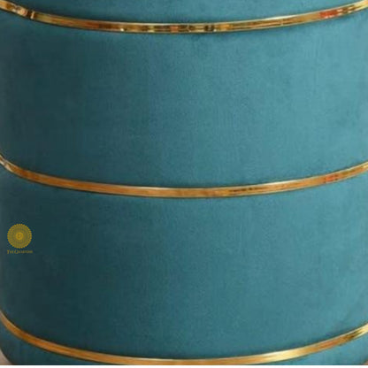 Light blue fabric ottoman pouffe stool by The Gharnish, featuring a soft, cushioned surface and rounded design.